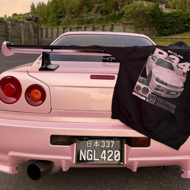 Customer wearing a custom car T-shirt featuring their Nissan Skyline R34, photographed next to their car.