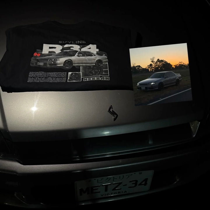 Customer wearing our custom car T-shirt featuring their Nissan Skyline R34, photographed next to their car.