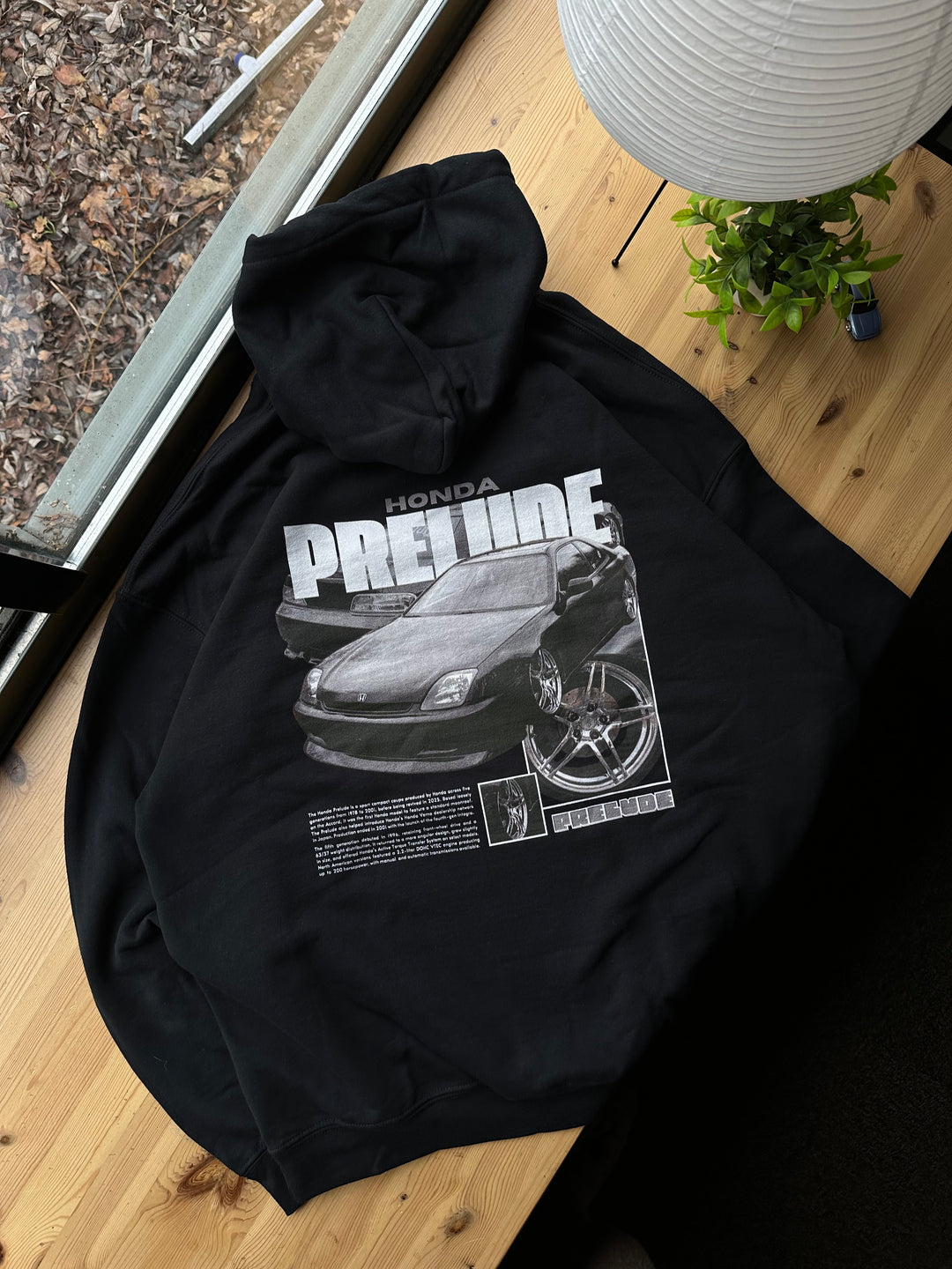 Black hoodie with Honda Prelude BB9 graphic on the back, picture of the rear, hoodie on desk 