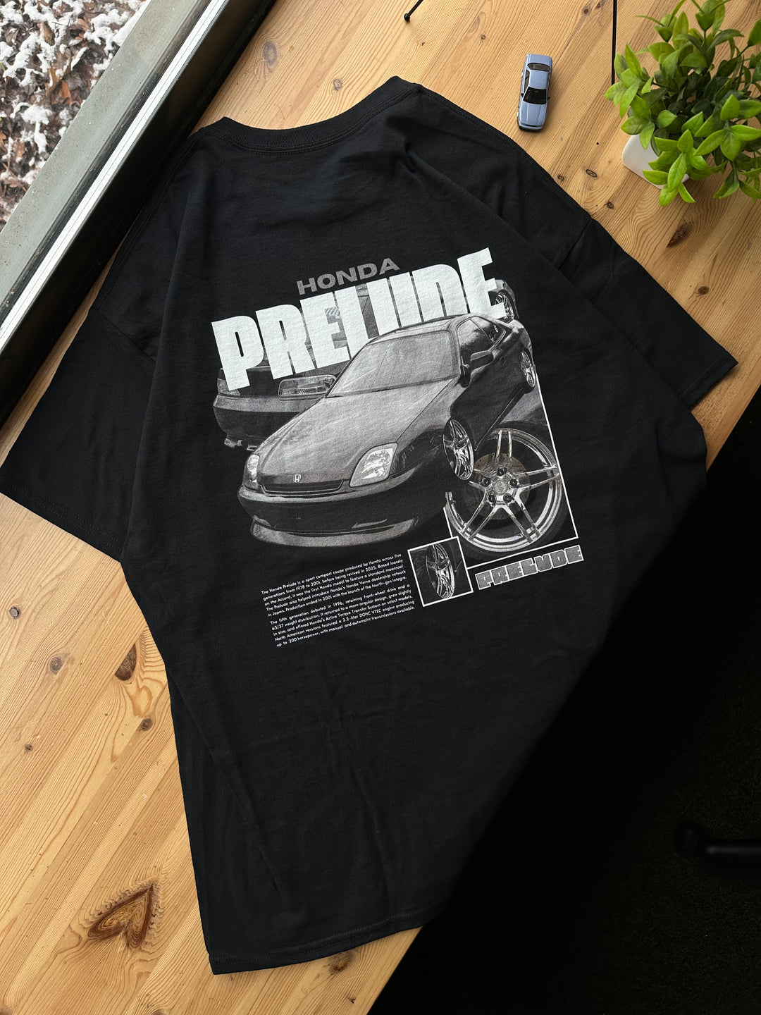 Black T-shirt with Honda Prelude BB9 graphic on the back, picture of the rear, T-shirt on desk